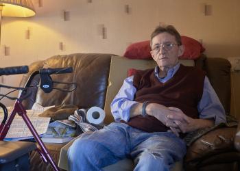 Man on couch in living room with zimmer frame
