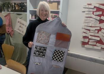 Person holding up piece of textile and smiling to the camera