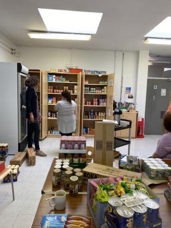 Community food pantry with shelves stocked with canned and packaged food.