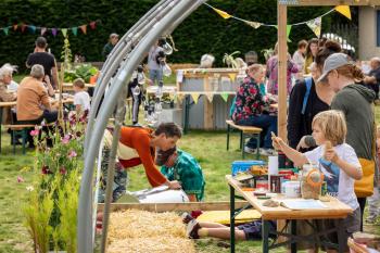 People gathered in a garden joining in on various activities such as crafting, chatting and playing.